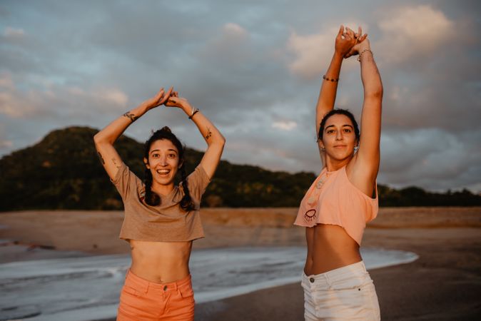 Women looking at camera on beach at sunset