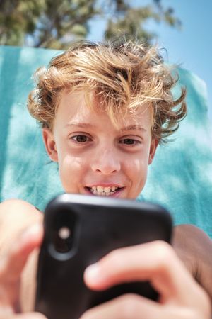 Excited boy using smartphone at poolside
