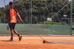 Man playing tennis doing court maintenance