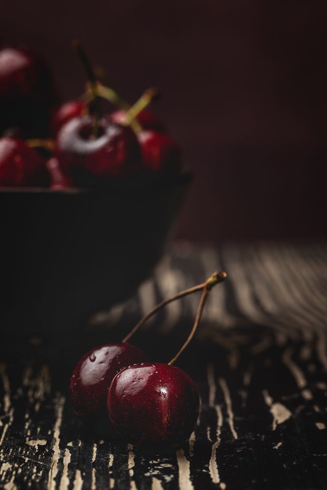 Juicy red cherry in bowl on rustic surface