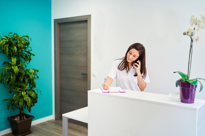 physiotherapist at the clinic reception desk talking on the phon