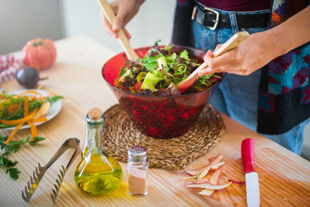 Crop woman preparing vegetable salad