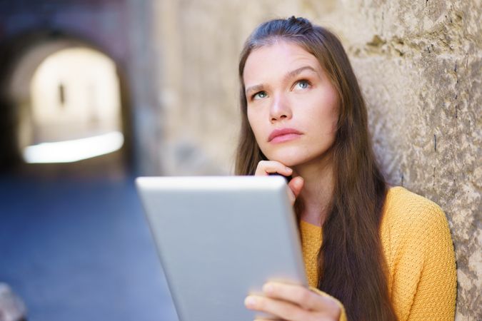 A Thoughtful Young Woman Engaged in Using a Tablet Within a Beautiful and Historic Setting