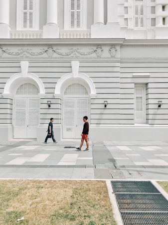 Side view of two young men standing beside light building in Singapore, Singapore