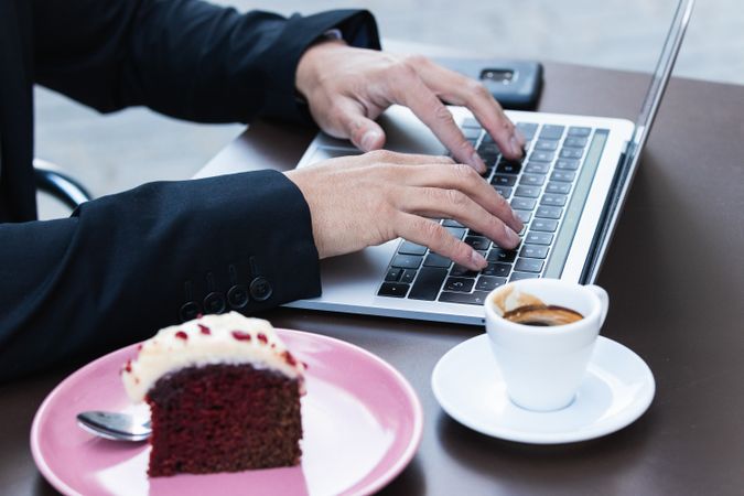 Anonymous male entrepreneur in suit working in cafe