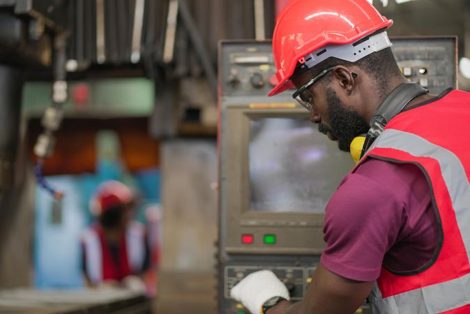 Man in PPE gear at screen of machinery he is operating