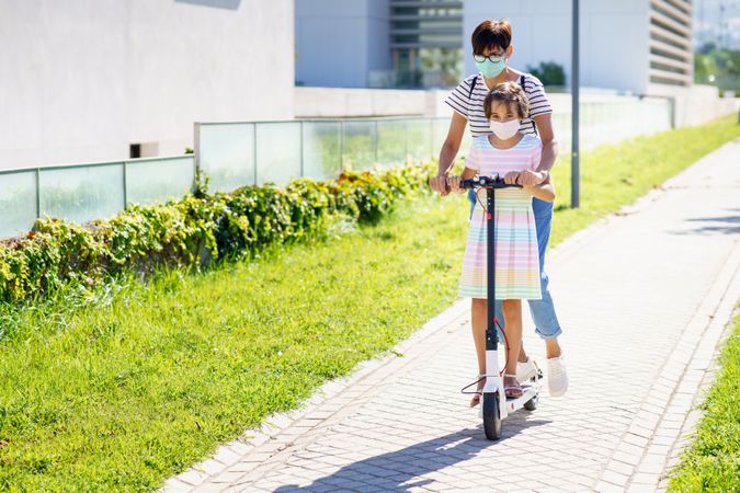 Mother and girl riding a scooter together