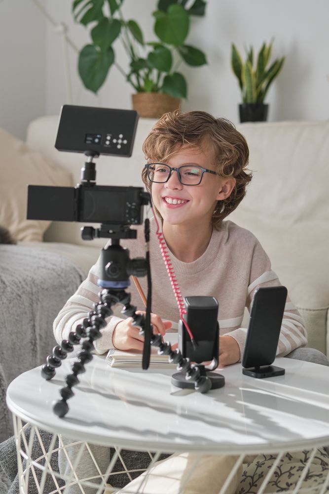 Smiling boy shooting video for blog using professional equipment