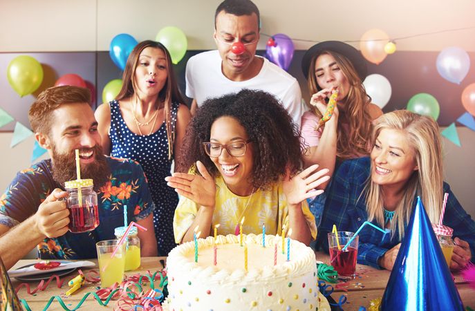 Group of people celebrating their friends birthday as she blows out candles
