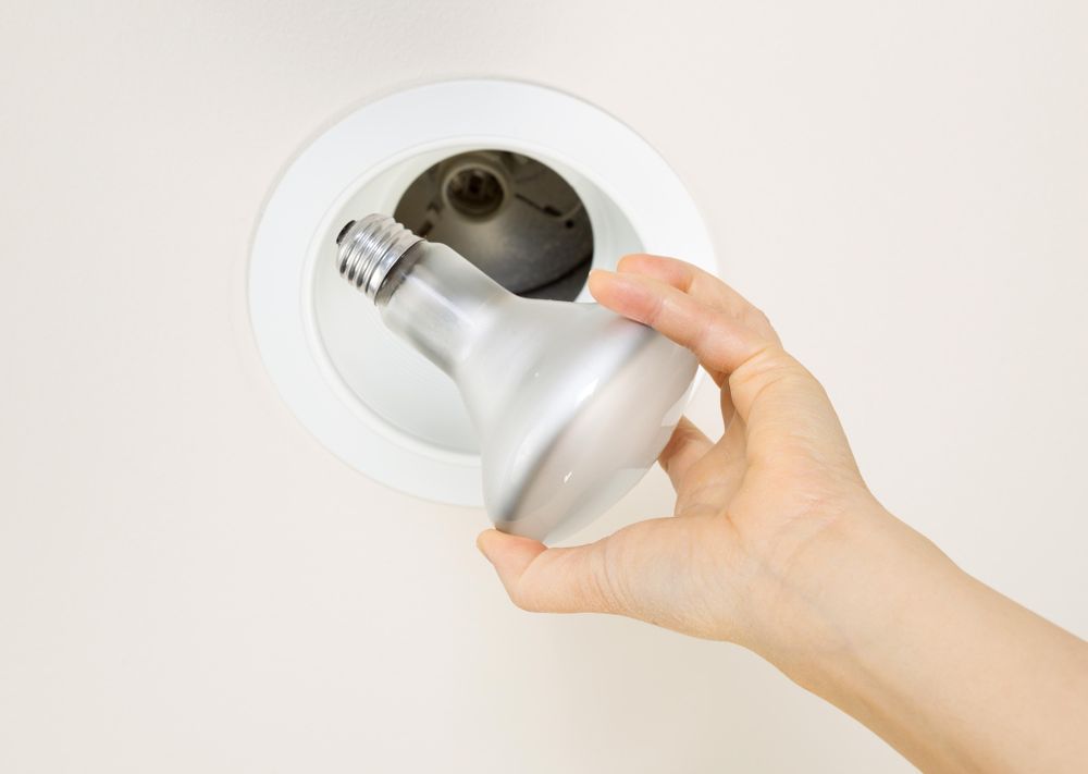 Old light bulb being removed from ceiling mount