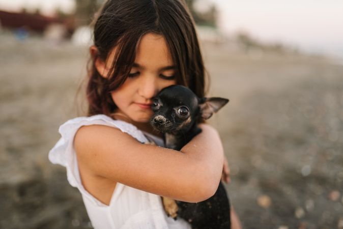 Girl with little dog on sandy beach