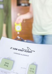 Woman checking luggage weight with a hand balance