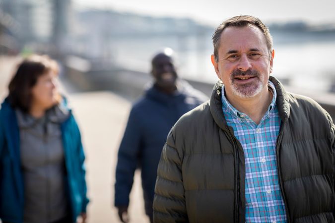 Man walking by the river with two friends behind him