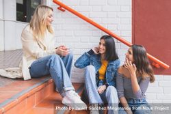 Three women having a conversation on outdoor brick steps 4jljz0