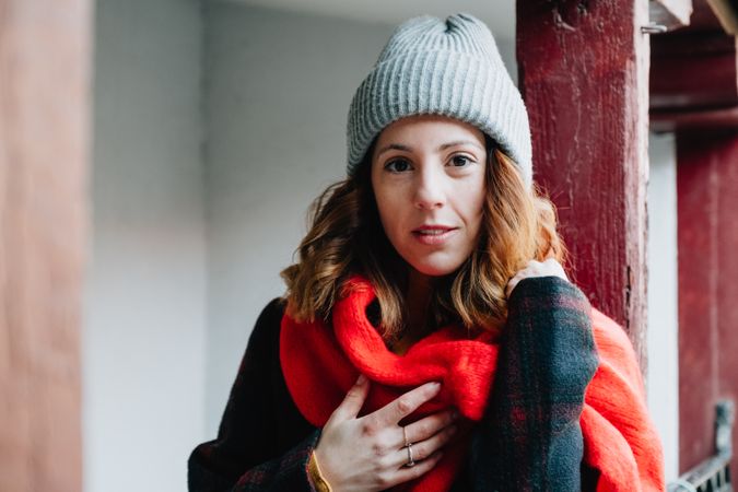 Positive woman in warm wear near house
