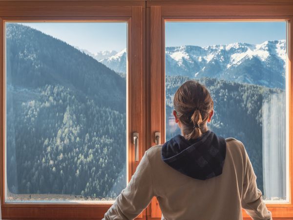 Anonymous woman looking at mountains from window