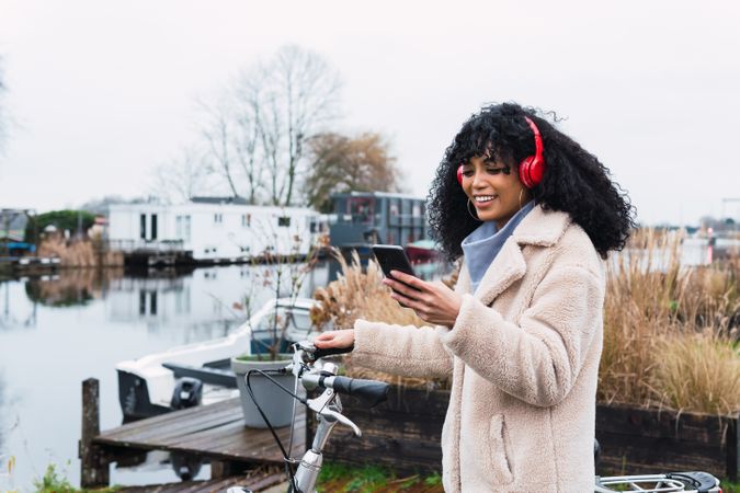 Delighted Black woman with smartphone on bicycle