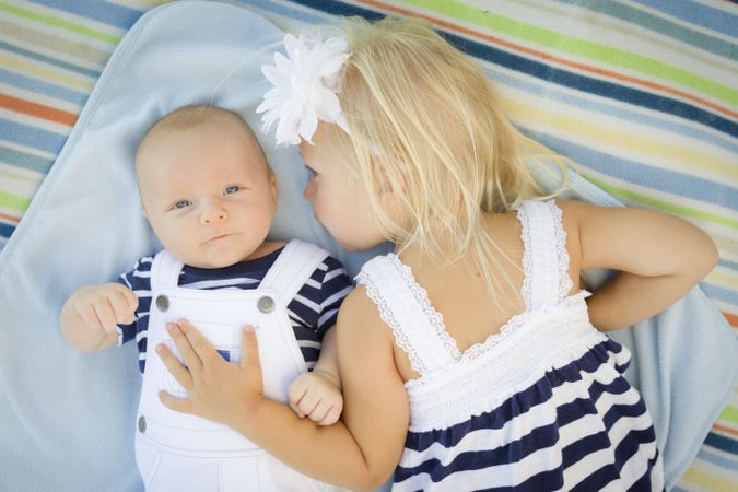 Little Sister Laying Next to Her Baby Brother on Blanket