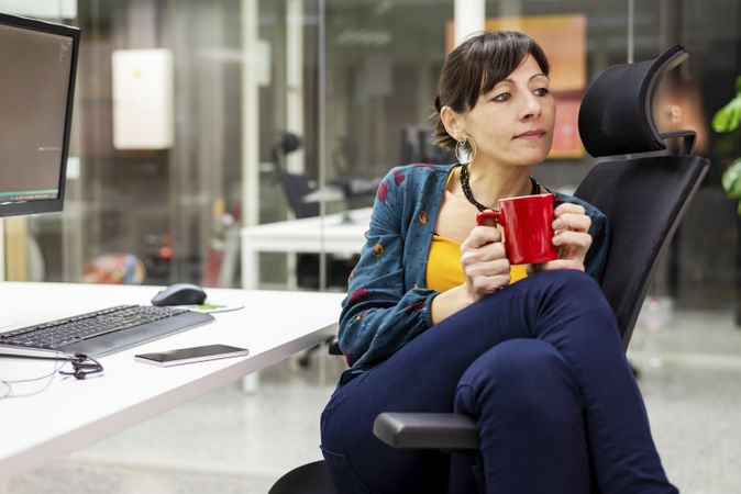 Smiling businesswoman with mug resting in office