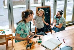 Family business owners taking a break playing with daughter in their cafe restaurant