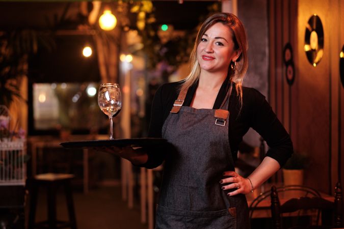 Cheerful waitress holding tray with wineglasses