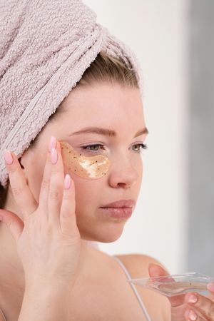 Applying eye patches in skincare routine.
