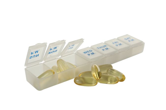 Omega tablets in a plastic organizer, isolated on blank background