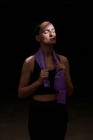 Sportswoman standing with resistance band under sunlight