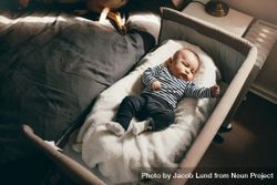 Infant lying in a bedside bassinet moving his hands and legs 5lRPeb