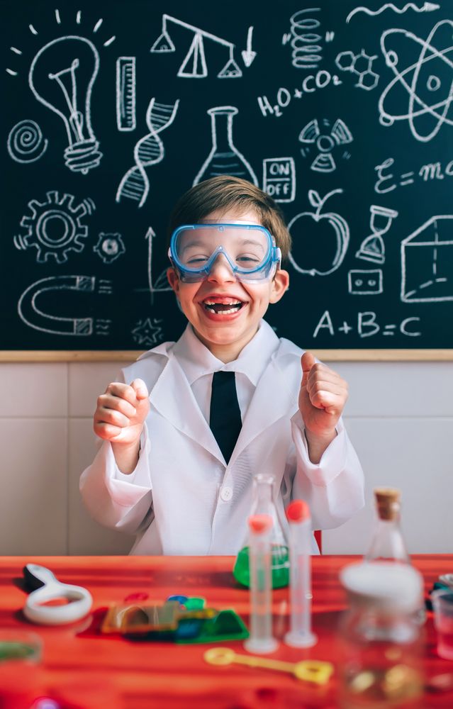 Happy kid with glasses laughing behind of experiments table