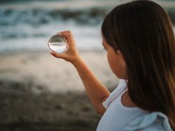 Girl playing with glass ball on seaside