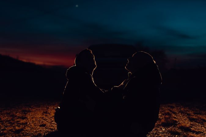 Men hugging and sitting on ground on field at night