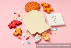 Flat lay paper cut out of side view of head with medications and puzzle pieces on pink background 5pdBO5