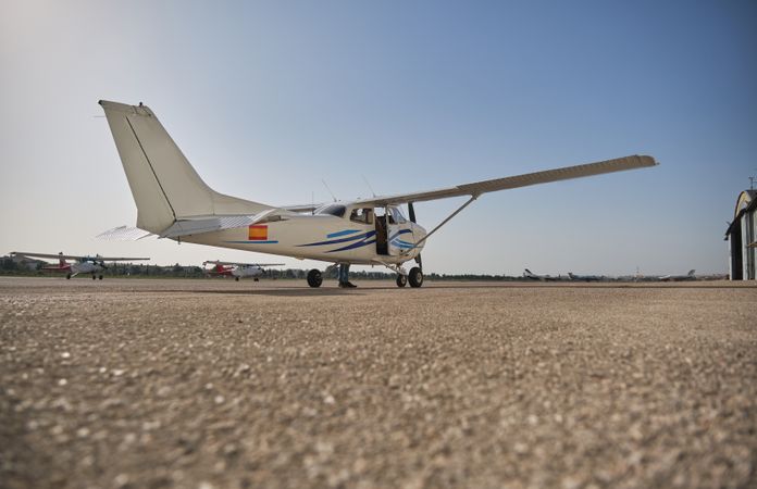High wing aircraft parked on runway under blue sky