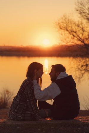 Couple sitting sunset lake