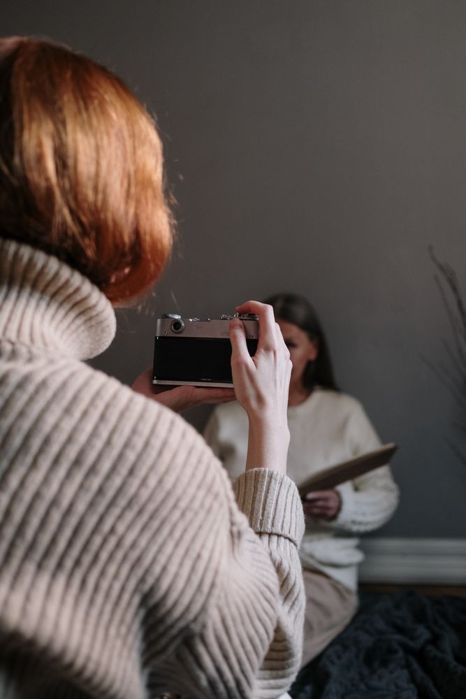 Back view of a photographer taking photo of woman reading a book