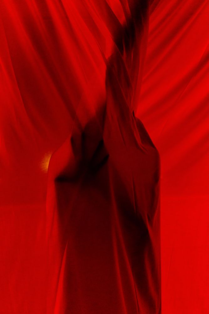 Faceless person hiding behind curtains at night time