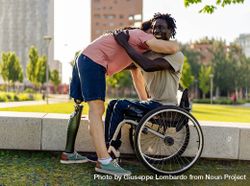 Men with disabilities embrace in a city park bGRNEY