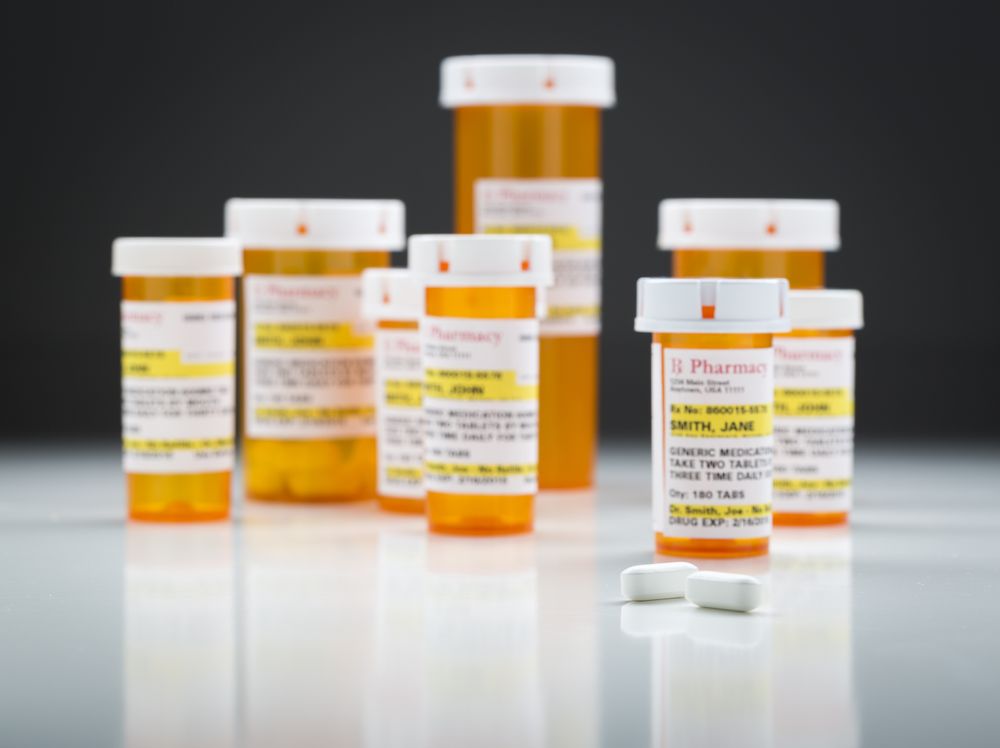 Medicine Bottles and Pills on Reflective Surface With Grey Background