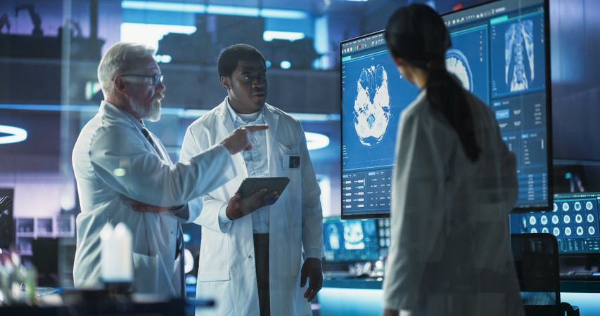 Medical Neuroscience Hospital Lab Meeting: Diverse Team of Neurosurgeons and Neurologists Analyze TV Screen Showing MRI Scan with Brain Images, Talk About Sick Patient Treatment Method, New Drugs Cure