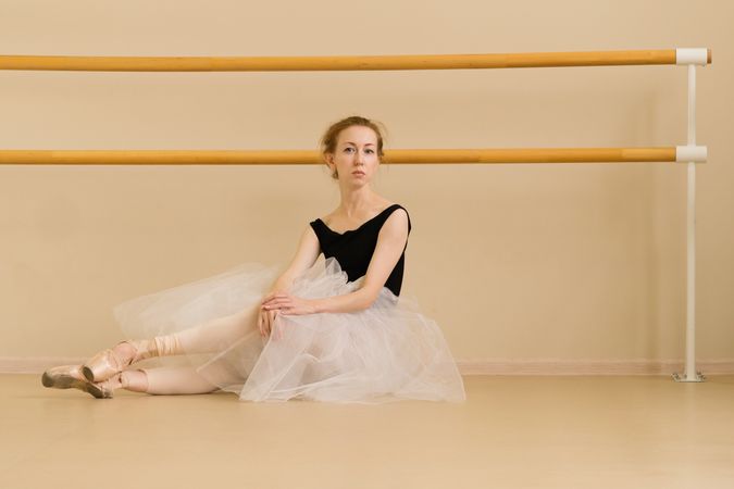 Ballet dancer sits on the floor in dance studio