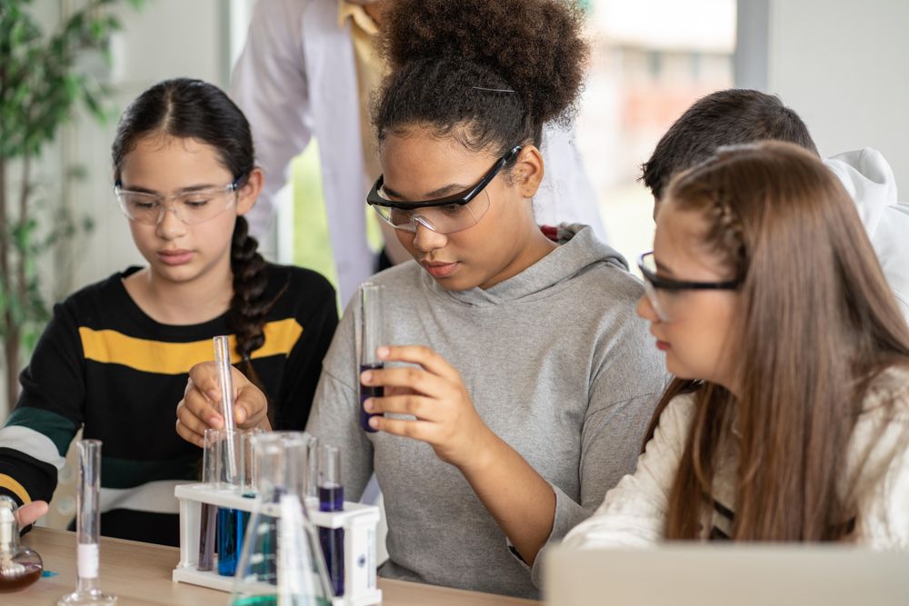 Three female students in science class doing chemical experiment in laboratory