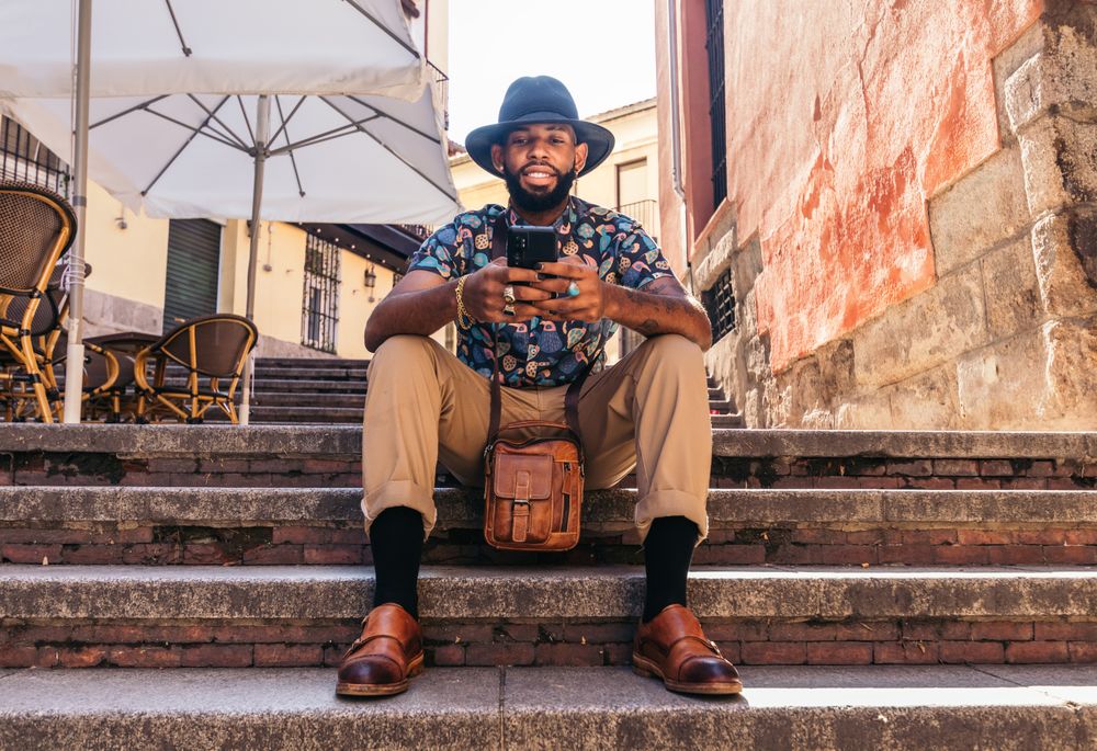 Stylish Black man in the city street using smartphone