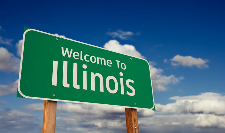 Welcome To Illinois Green Road Sign Over Blue Sky with Some Clouds.