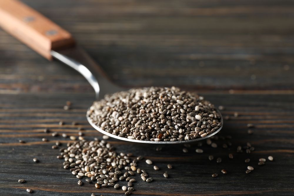 Spoon with chia on wooden background, copy space