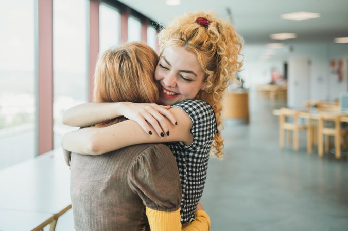 Happy teen students hugging in library