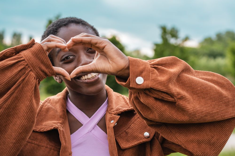 Joyful Black woman making heart shape with hands
