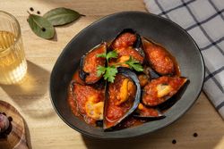 Cooked plate of mussels in tomato sauce on table