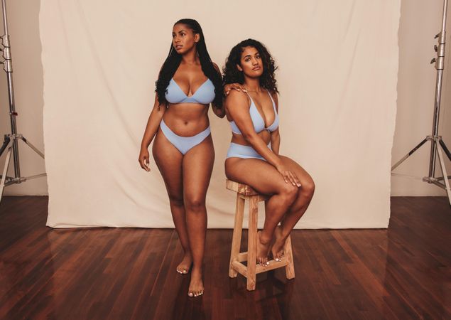 Body positive young women posing against a studio background