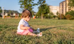 Happy baby girl playing sitting on a grass park